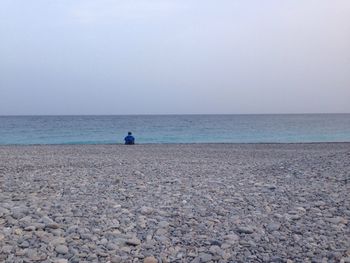 Rear view of man looking at sea against sky