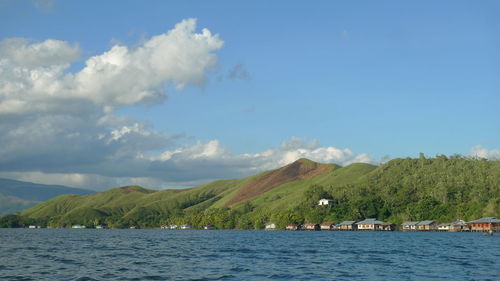 Scenic view of sea by mountains against sky