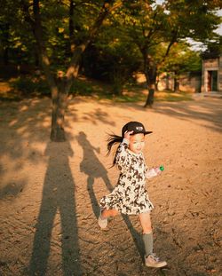 Full length of smiling young woman with shadow on tree