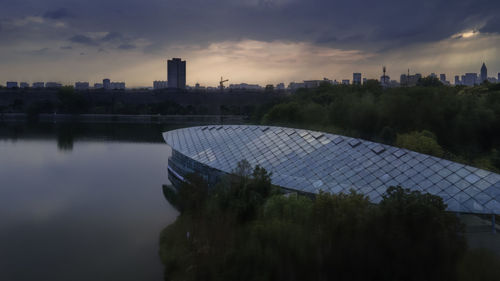 Scenic view of lake by buildings against sky at sunset