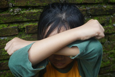 A child is covering his face with his arms crossed