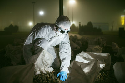 Scientist wearing protective workwear working outdoors at night