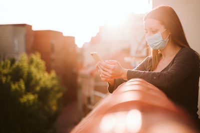 Woman using smart phone while standing in balcony