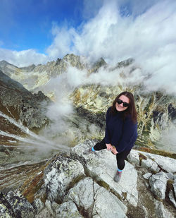 Portrait of young woman standing on mountain against sky