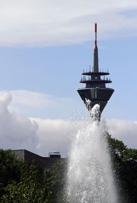 Rheinturm in düsseldorf, germany, hidden behind a water fountain on a sunny day