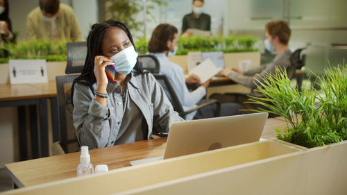 Woman using phone while sitting on table