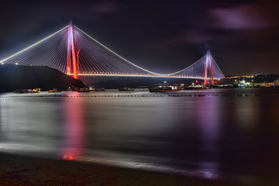 Illuminated bridge over river at night