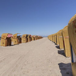 Hooded beach chairs against clear blue sky