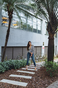 Woman standing by palm trees