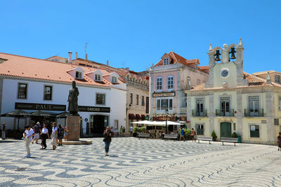 People walking on street against buildings in city