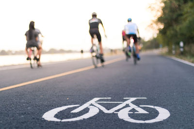 Rear view of people riding bicycles on road