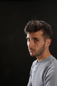 Portrait of young man against black background
