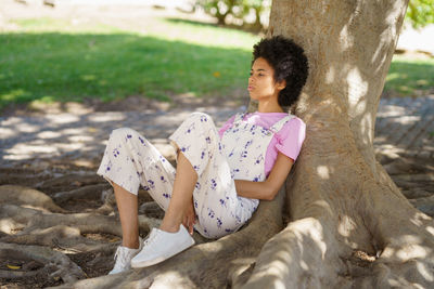 Young woman sitting on tree trunk