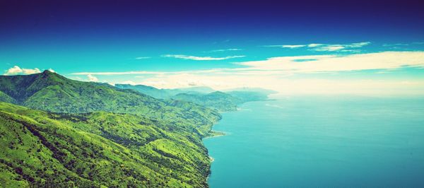 Scenic view of sea and mountains against blue sky