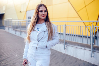 Smiling beautiful young woman standing against building