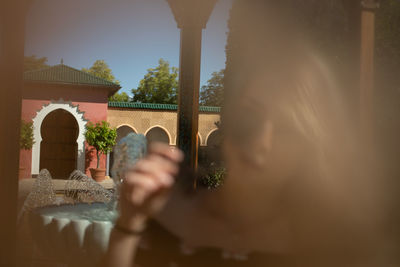 Portrait of woman holding glass window of building