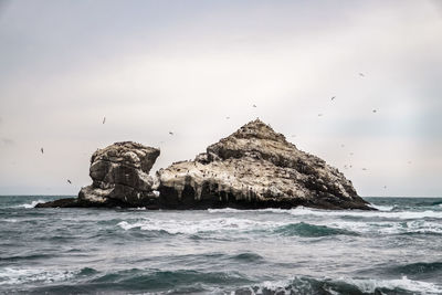 View of rock formation in sea against sky