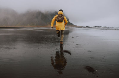 Rear view of man running on shore at beach