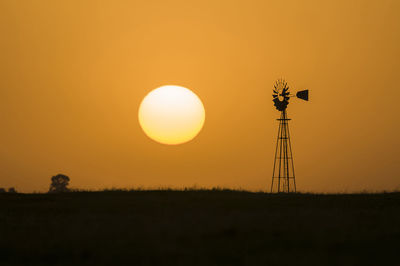 Scenic view of silhouette field against orange sky