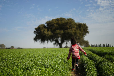 Rear view of woman standing on field against sky