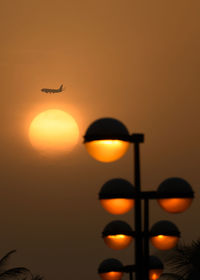 Low angle view of silhouette airplane against orange sky