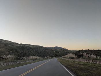 Empty road along landscape against clear sky