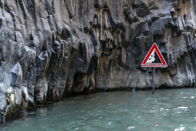 Warning sign in sea by rock formation