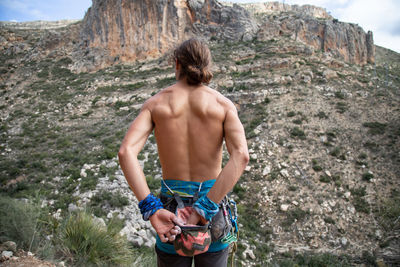 Rear view of shirtless man standing on rock