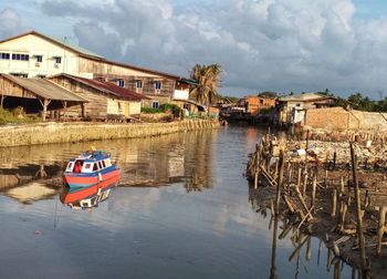 Nautical vessel on river by buildings against sky