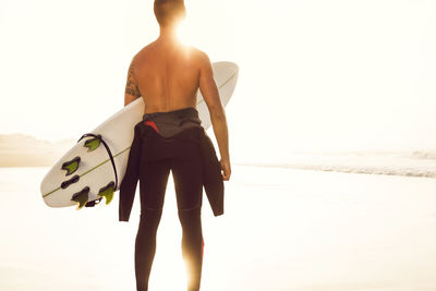 Rear view of shirtless man standing on beach