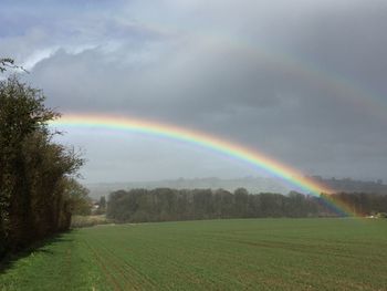 Scenic view of rainbow over field against sky