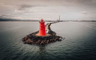 Lighthouse by sea against sky