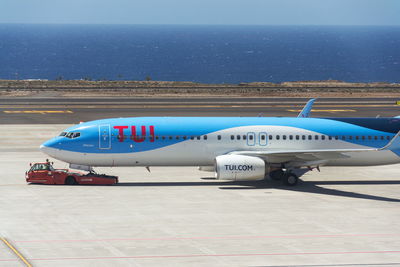 Airplane on airport runway against sky