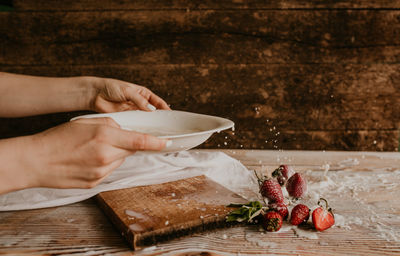 Cropped hand of person preparing food on table