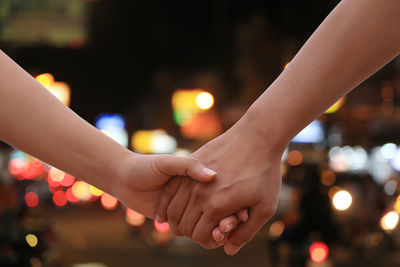 Close-up of hands on illuminated at night