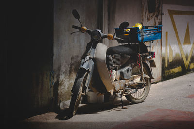 Motor scooter parked against wall in city