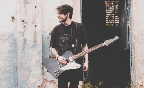 Man playing guitar against wall