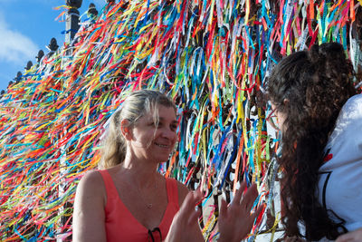 Portrait of two women placing colored ribbons on the church grid. 