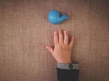 Cropped hand of child by blue plastic toy on table