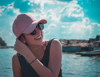 Close-up of cheerful young woman sitting by sea