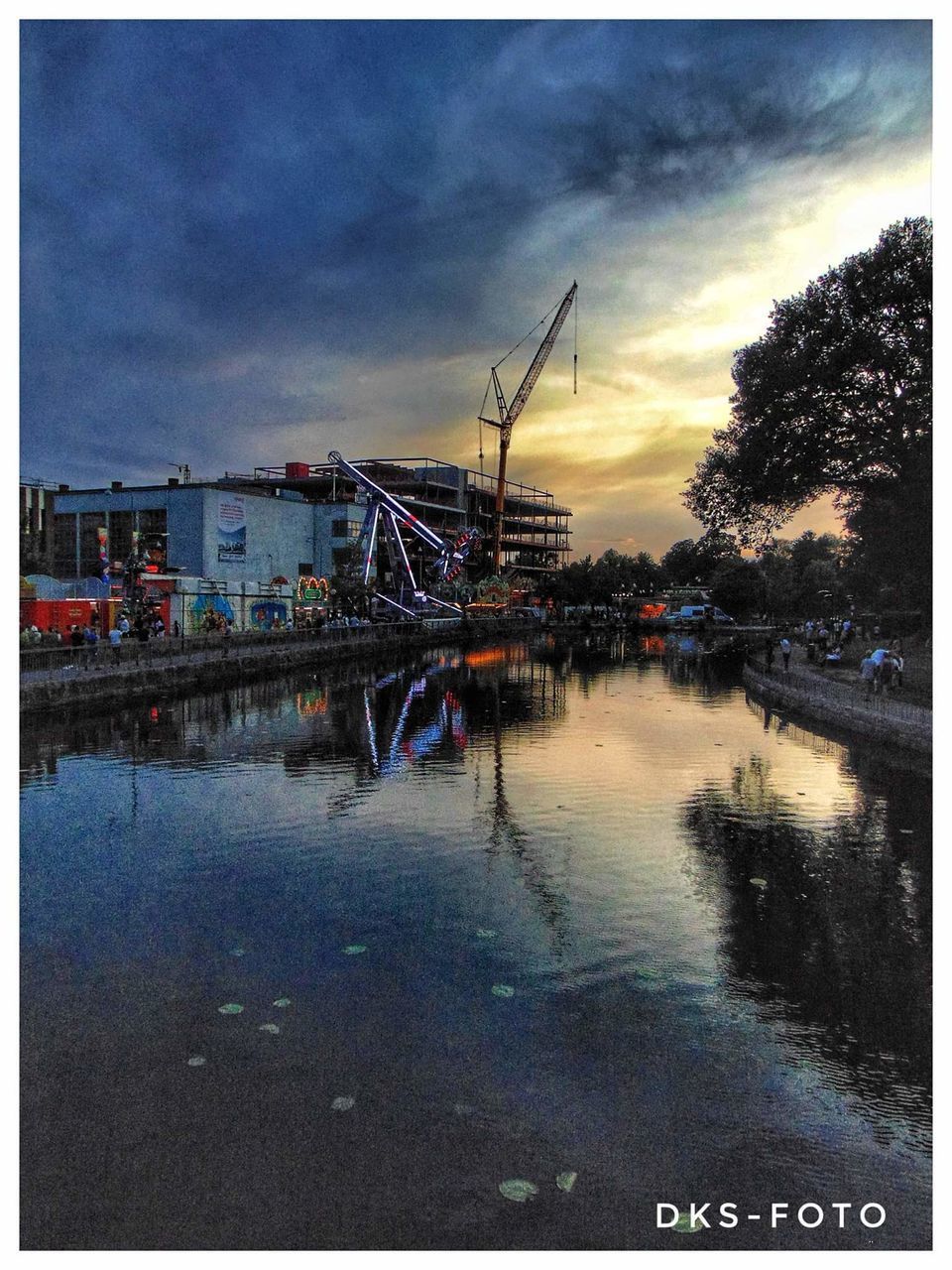 ILLUMINATED CITY BY RIVER AGAINST SKY AT DUSK