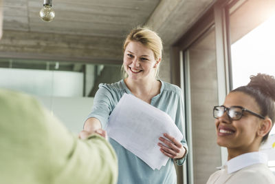 Young woman in office shaking hands with colleague