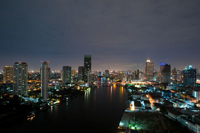 Illuminated buildings in city against sky at night