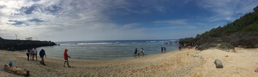 Panoramic view of people on beach against sky