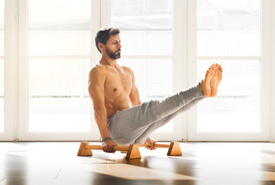 Shirtless man exercising by window in gym