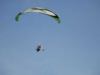 Low angle view of person motor paragliding in clear sky