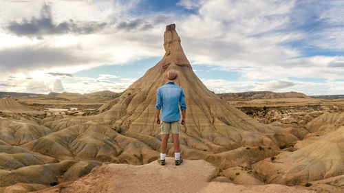 Rear view of man standing on rock against sky