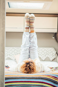 Rear view of woman sitting on bed at home