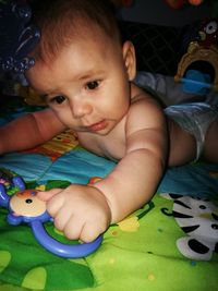 Portrait of cute boy playing with toy on bed