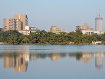 Reflection of buildings in lake against clear sky